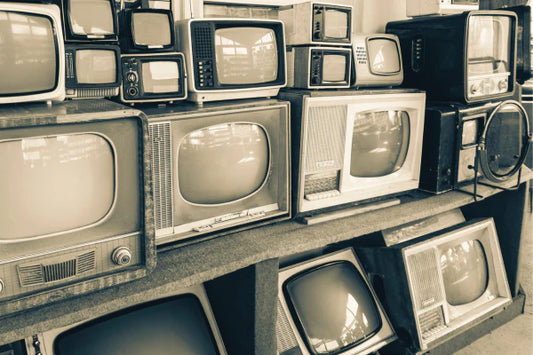 A black and white image of old portable  tvs from the 1970's and 1980's