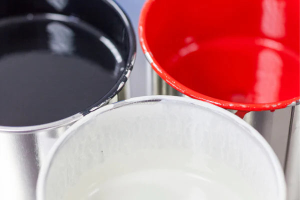 A closeup of three open cans of paint. Black, Red, White, respectively.