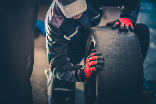 A human inspecting a used racing car tire