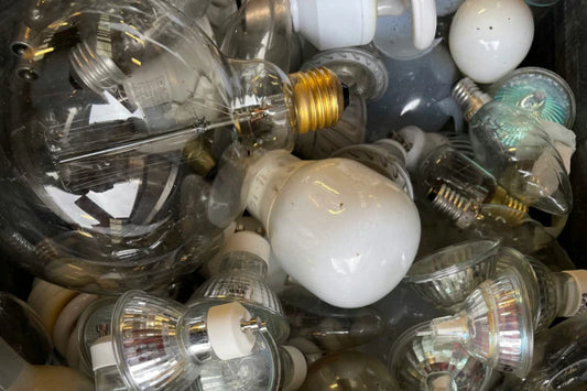A closeup of a pile of spent light bulbs. There are many different kinds of light bulbs in this pile. Too many to name.