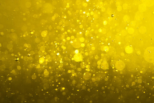 Closeup of a solvent of unknown type. Goldish yellow in color, the solvent or liquid contains various sizes of air bubbles.