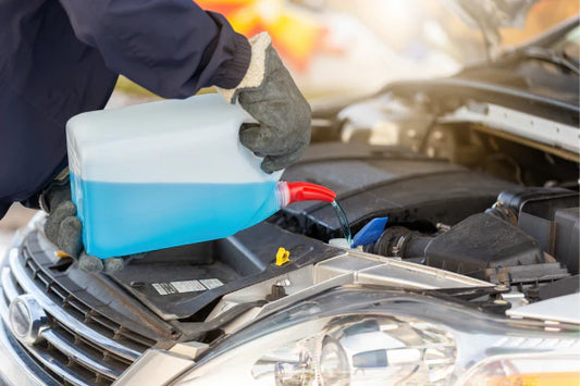 A closeup of an auto mechanic filling a cars engine with anti-freeze