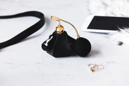 A closeup of a beautifully designed black and gold perfume bottle